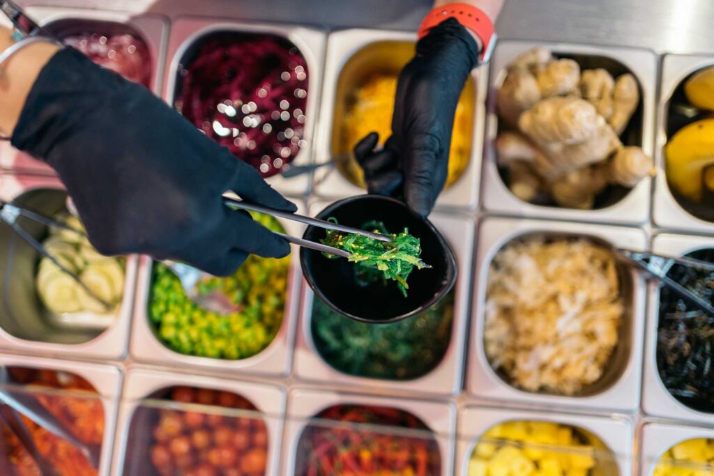 Photo showcasing options for customizable poke bowl catering services, with different ingredients on display.
