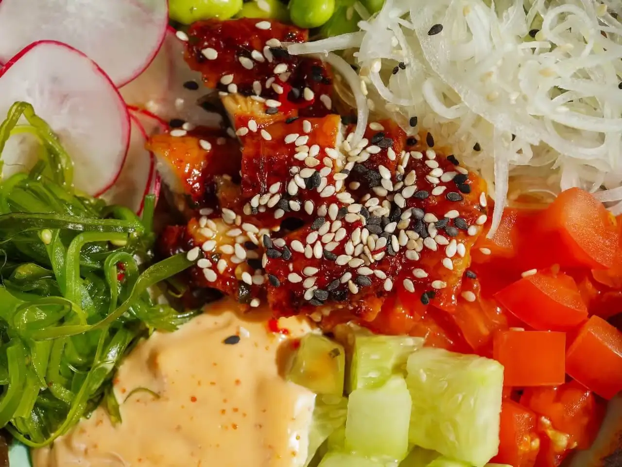 Colorful poke bowl with marinated fish, seaweed, radish, cucumber, and topped with sesame seeds at Poke Bowl NY.
