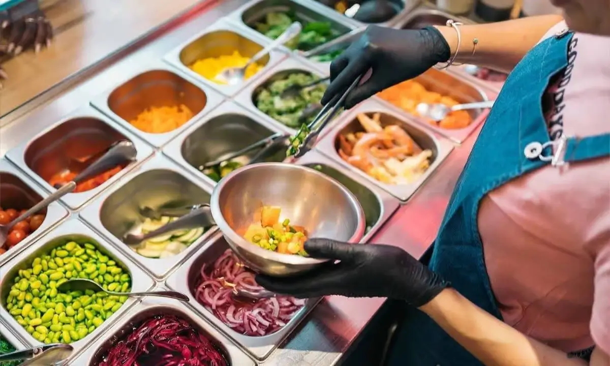 Creating a customized poke bowl with fresh ingredients and toppings selection.