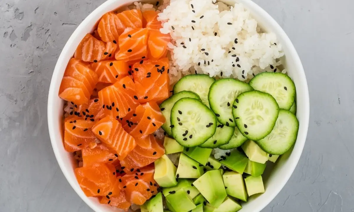 Salmon poke bowl with rice, cucumber, avocado, and sesame, showcasing fresh ingredients for a quick, healthy meal.