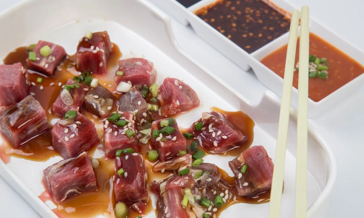 Tuna poke with soy-sesame sauce, garnished with green onions and sesame seeds, highlighting poke sauce flavors.