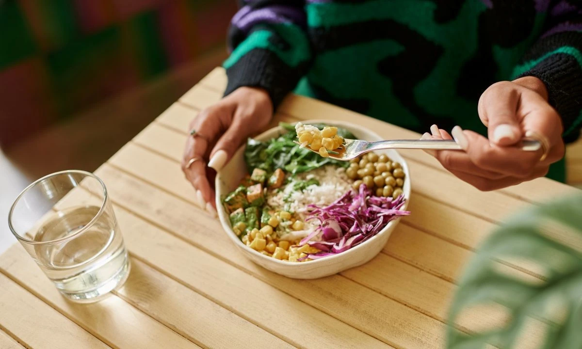 Vegan poke bowl with rice, cabbage, greens, and corn on a wooden table, highlighting plant-based eating.