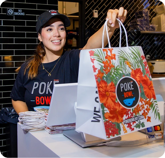 Poke Bowl employee handing Crack Rice takeaway bag at pickup counter