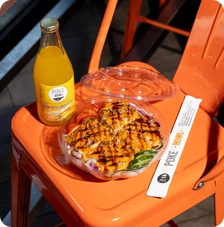 Keto poke bowl takeout from Poke Bowl with pineapple drink on orange chair