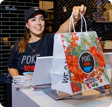 Poke Bowl NY employee handing vegetarian poke bowl takeout bag at counter